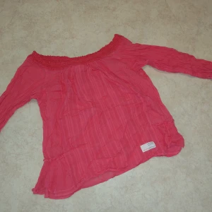 Offshoulder blus - Supersöt rosa blus från Odd Molly med offshoulder-modell och långa ärmar. Blusen har diskreta ränder i tyget och en smockad kant upptill som ger en snygg passform. Luftigt material som passar perfekt till vår och sommar. Knappt använd, men tyvärr lite skrynklig. Står ingen storlek men passar en s/m