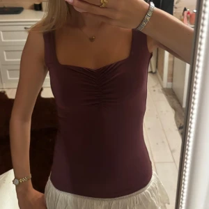 Vinröd linnetopp från BubbleRoom - Säljer en vinröd linnetopp från BubbleRoom med breda axelband och snygg rynkdetalj framtill. Toppen har fyrkantig urringning och är figurnära i modellen. Perfekt att styla med kjol eller jeans för en trendig look.