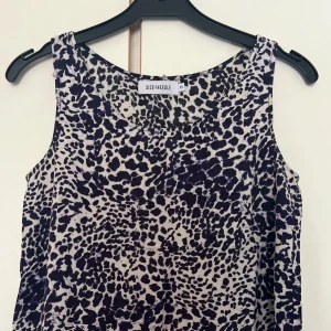 Leopardmönstrad linnetopp från Size Needle - Snygg ärmlös linnetopp från Size Needle i svartvitt leopardmönster. Toppen har rund halsringning och är tillverkad i ett lätt och luftigt material, perfekt för att sticka ut med en cool look. Passar dig som gillar djurmönster och vill ha en trendig vibe.