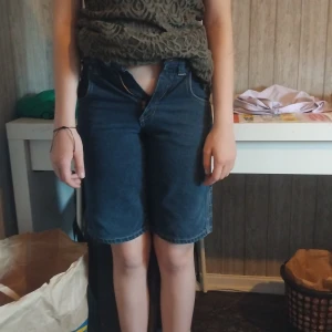 Blå jeansshorts från Phat Denim - Snygga blå jeansshorts från Phat Denim med coola detaljer och stora bakfickor. Klassisk femficksmodell med logga på fickor och insida. Raka ben och normal passform, perfekta för en chill streetwear-look.