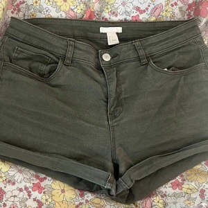 Olivgröna jeansshorts från H&M - Snygga olivgröna jeansshorts från H&M i klassisk femficksmodell. De har låg midja/midwaist uppvikta ben och råa kanter för en avslappnad vibe. Materialet är mjuk bomull med lite stretch för extra komfort. Perfekta för varma dagar och enkel att matcha med allt.