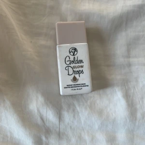 W7 Golden Glow Drops bronzer - Golden Glow Drops från W7 ger en snygg solkysst look med sina bronzande droppar. Kommer i en smidig vit plastflaska med beige lock och innehåller 30 ml flytande produkt som ger huden en strålande finish. Aldrig använd, smutsig då den legat i min sminklåda men torkas såklart av!