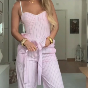 Ljusrosa randiga byxor med knyt - Superfina byxor med tunna vertikala ränder och knyt i midjan. De har en avslappnad passform, perfekt för varma dagar. Aldrig använt