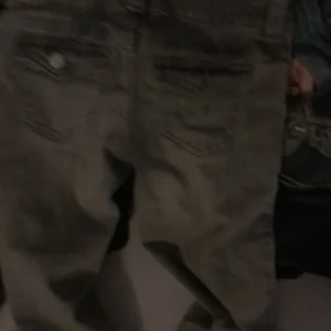 Grå jeans med raka ben - Säljer ett par grå jeans med klassisk femficksdesign och raka ben. Byxorna har en enkel look och passar perfekt till en avslappnad stil. Färgen är mörkgrå och materialet är slitstarkt denim.