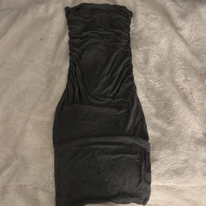 Mörk grå axelbandslös klänning  - Säljer en mörk grå axelbandslös klänning med tight passform. Tror att de är storlek S men inte säker 