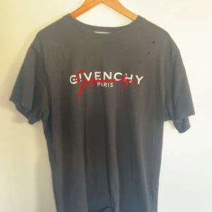 Givenchy t-shirt - Svart t-shirt från Givenchy med vit och röd logga på bröstet. Klassisk rund halsringning och korta ärmar. T-shirten är i mjuk bomull och har en clean, stilren look med en touch av streetstyle.
