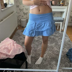 Blå volangkjol - Supersöt ljusblå kortkjol med volanger och bred smock i midjan. Kjolen har en flowy känsla och är perfekt för varma dagar. Super söt💕💕