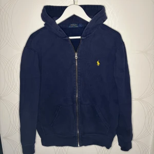 Ralph Lauren Zip - Marinblå Zip hoodie med dragkedja från Polo Ralph Lauren i storlek L. Klassisk modell med gul logga, sparsamt använd och i fint skick.  Hör av dig vid intresse! 🙌