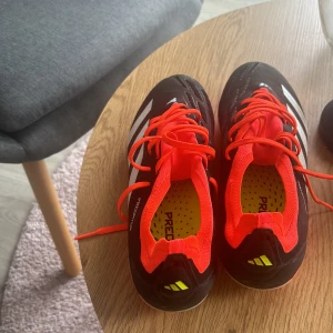 Adidas Predator fotbollsskor - Säljer ett par svarta Adidas Predator fotbollsskor med röda snören och vita detaljer. Använda 2 gånger:)