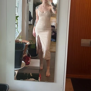 Beige linneklänning med slits och smala axelband - Säljer en beige linneklänning med smala axelband och markerad byst. Klänningen har en snygg slits framtill och figurnära passform som framhäver siluetten. Perfekt för dig som gillar minimalistisk och stilren design.