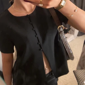 Svart kortärmad blus med knappar - Snygg svart blus med korta ärmar och dekorativa knappar framtill. Perfekt för en stilren look. (Återompublicerad) ❤️
