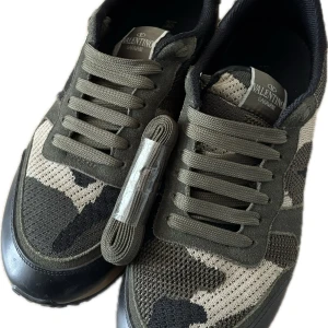 Valentino Rockrunner sneakers i camouflage - Säljer ett par Valentino Rockrunner sneakers i grönt och beige camouflage-mönster. . 9,5/10 skick. Varit inne i en vecka. Kom gärna med bud eller byten! Priset är ej hugget i sten, Vi vill få bort skorna ASAP :) Mvh Sami.                                OBS! Endast extra snöre och skor medföljer.
