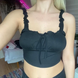 svart topp - snörning i fram och  volang-detaljer