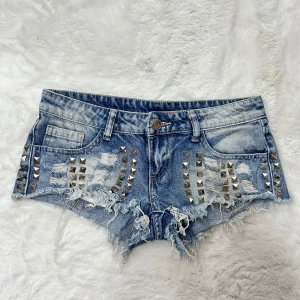 Lågmidjade jeansshorts med hål och nitar / minishorts y2k 2000s - Supersnygga och unika jeansshorts med nitar och hål. Storlek s enligt lapp, något små i storleken enlig mig . Midjemått:37. Köp sker via köp nu, jag postar inom 24h. Kvar tills markerad såld 