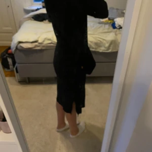 Svart stickad klänning från Vila - Svart stickad klänning från Vila i storlek S. Klänningen har lång ärm och slits på sidan, vilket ger en snygg detalj. Perfekt för dig som gillar en enkel men stilren look.