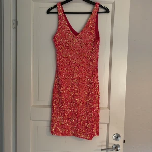 Rosa paljettklänning från Bik Bok - Säljer en handgjord, tight rosa klänning från Bik Bok täckt med glittrande paljetter. Klänningen är ärmlös med v-ringning fram och bak. Totallängd fram 66cm. Superskön figurnära passform helt oanvänd, nypris 699kr 