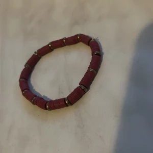 Rosa armband med gulddetaljer - Säljer ett armband med rosa pärlor och små guldfärgade detaljer mellan varje pärla. Perfekt accessoar för att addera lite färg till din outfit.