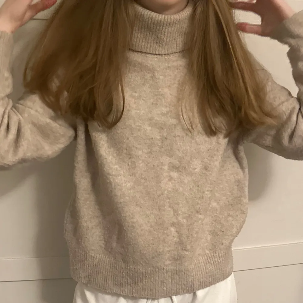 Säljer en mysig beige polotröja med hög krage. Tröjan är stickad och har en avslappnad passform, perfekt för kyliga dagar. Enkel och stilren design som passar till det mesta.. Neuletakit & Villapaidat.