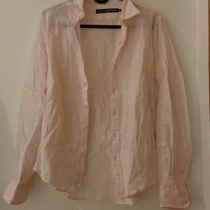 Ralph lauren linneskjorta  - Säljer en ljusrosa skjorta från Ralph Lauren med klassisk krage och knappar framtill. Skjortan har långa ärmar och är tillverkad i ett lätt och bekvämt material. Perfekt för en stilren look.