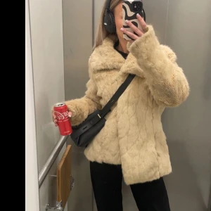 Beige pälsjacka med krage - Säljer en fluffig beige pälsjacka med stor krage. Jackan har lång ärm och stängs framtill. Perfekt för kyligare dagar och ger en lyxig känsla till outfiten.