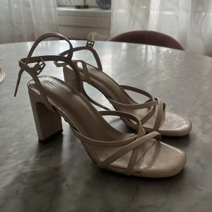 Beigea klackskor - Säljer ett par stilrena beige sandaler från XIT med fyrkantig tå, bred klack och smala remmar som korsas över foten. Använd en gång och är i jätte bra skick 😍