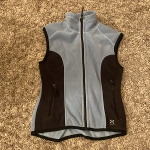 Ljusblå fleeceväst från Haglöfs - Säljer en ljusblå och svart fleeceväst från Haglöfs med hög krage och hel dragkedja framtill. Västen har två fickor med dragkedja och är perfekt för lager-på-lager. Klassisk sportig design.