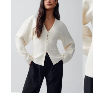 Vit kofta med knappar och v-ringning - Säljer en stilren vit kofta med v-ringning och knappar framtill. Tröjan har lång ärm och är tillverkad i ett mjukt material som ger en clean look. Perfekt att styla med både jeans och kostymbyxor.