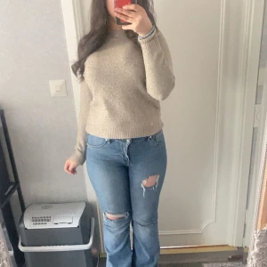 Beige stickad tröja från Vero Moda - Mysig beige stickad tröja från Vero Moda. Tröjan har rund halsringning och långa ärmar med ribbade muddar. Perfekt för lager-på-lager och enkel att matcha med jeans eller kjol.
