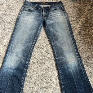 Blå bootcut jeans från 7 For All Mankind - Ett par blå bootcut jeans, lågmidjade super snygga, sälj för att de är försmå!      Midjemått: 38cm Innerbens längd: 78cm