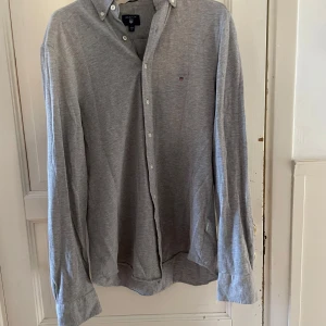 Grå skjorta från GANT - Säljer en stilren grå skjorta från GANT i storlek S. Skjortan har långa ärmar och knappar framtill. Perfekt för en klassisk look.