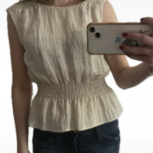 Beige blus med smock från Kappahl - Supersöt beige blus från Kappahl i storlek XS. Toppen har smock i midjan och vid axlarna. Knappt använd!