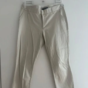 Ljusbeige byxa - Snygga ljusbeige byxor med normal passform och raka ben. Byxorna har hällor för bälte, sidfickor fram och två bakfickor. Perfekta för en clean och stilren look