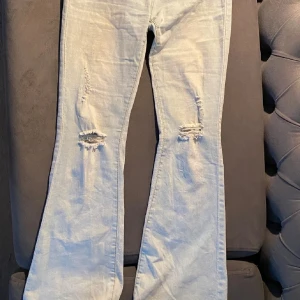 Ljusblå bootcut jeans med slitningar - Såå snygga jeans med hål! Dom passar perfekt för mig som är 165, sjukt snygga och har en ganska stretchig material! Köpte dem på plick.