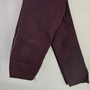 Vinröda cargopants från Esmara - Snygga vinröda cargopants från Esmara med praktiska fickor på benen och dragkedja vid benslut. Byxorna har en loose fit och är tillverkade i mjuk bomull, perfekta för en chill och avslappnad stil.
