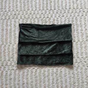 Mörkgrön sammettopp/kjol med volanger - Supersnygg mörkgrön kjol/topp i sammet med tre breda volanglager. Kjolen har en tight passform och ger en lyxig känsla tack vare det glansiga materialet. Den är sydd av mig!