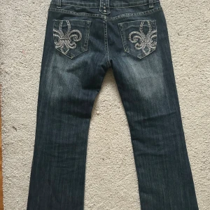 Lågmidjade bootcut jeans - As snygga mörkblå jeans som liknar miss me. Endast använda ett fåtal gånger och därför i väldigt bra skick, endast någon kristall som lossnat på bakfickan. Säljer då de tyvärr är för stora för mig som vanligtvis har xs/s i jeans💗