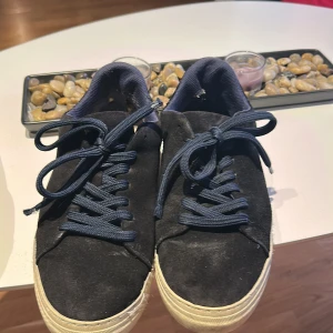 Mörkblåa sneakers  från Selected Homme - Mörkblåa  sneakers från Selected Homme i mocka med mörkblå snörning och vit sula. Klassisk rund tå och platt sula, perfekt för en clean och stilren look. Storlek 42. Passar dig som gillar minimalistisk stil. Man kan borsta bort det smutsiga super smidigt och enkelt och är jätte bra och fina skor 