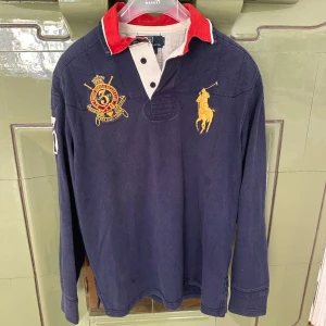 Blå Långarmad Ralph Lauren tröja Vintage - Säljer en sällsynt blå Ralph Lauren tröja i väldigt bra skick! 💸 Nypris: ca 2000 kr 🚚 Snabb frakt! Skickas inom 1–2 dagar ✅ Inga fläckar, hål eller synliga tecken på slitage.   💬 Skriv gärna vid frågor – jag svarar snabbt!