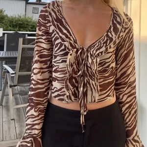 Zebramönstrad blus - Blus i zebramönster med volanger och snören man knyter där fram. Har tyvärr klippt av prislappen men den är helt oanvänd 🤎
