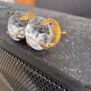 Stora glittriga örhängen med kristall - Säljer ett par stora örhängen med rund, slipad kristall i mitten och guldfärgade detaljer. De har en riktigt glittrig look och är perfekta om du vill sticka ut. Snygga att matcha med både streetwear och mer dressade outfits.