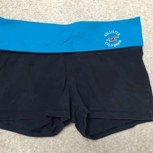 Hollister fold over shorts  -  Säljer ett par hollister fold over shorts i XS! Den är svart med en blå midja och är lågmidjade ❣️