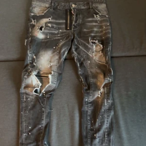 Dsquared2 svarta distressed jeans - Riktigt feta svarta jeans från Dsquared2 med slitna detaljer, hål och färgstänk för en rå streetlook. Jeansen har dragkedja, klassisk femficksdesign och Dsquared2-logga bak. Materialet är jeans i bomull och passformen är slim. Kan sänka priset med snabb handling! 