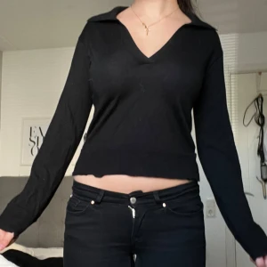 Svart v-ringad långärmad tröja - Svart långärmad tröja med v-ringning och krage. Tröjan har en croppad passform som visar lite av magen💓