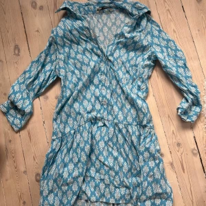 Blå mönstrad kortklänning från zara - Supersöt blå kortklänning med vitt blommönster från zara. Mycket bra skick.