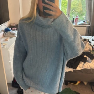 Ljusblå stickad polotröja från Dilvin - Supermysig ljusblå stickad polotröja från Dilvin. Tröjan har oversized passform, bred polokrage och långa ärmar. Perfekt för lager-på-lager och chill dagar. Ribbstickad struktur som ger en snygg och avslappnad vibe.