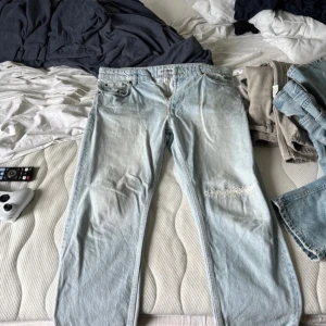 Ljusblå jeans från Just Junkies - Ljusblå jeans från Just Junkies med klassisk femficksdesign och slitning på ena knät. Jeansen har raka ben och är av ”Cropped-stil” och är tillverkade i bomull. Perfekta för en avslappnad och trendig look. 