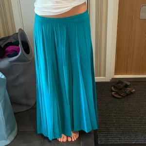 Turkos långkjol med resårmidja - Säljer en turkos långkjol då den krympte i tvätten. Skulle säga att den passar för någon som är 165 eller kortare. 