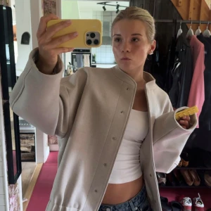 Beige oversized filtjacka - Säljer en beige jacka med oversized passform och stilrena knappar framtill. Jackan har en rak, enkel design utan krage och är långärmad. 