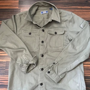 Olivgrön overshirt från Jack & Jones - DM FÖR BILD PÅ. Snygg olivgrön overshirt från Jack & Jones. Storlek S men passar xs också. Perfekt nu till hösten och våren.