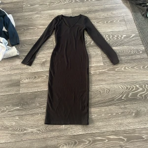 Svart ribbad långklänning 157 XS - Svart långklänning från 157 i storlek XS. Klänningen är ribbad, har lång ärm och v-ringning. Sitter tight och har en stilren, enkel look som funkar till många olika stilar.